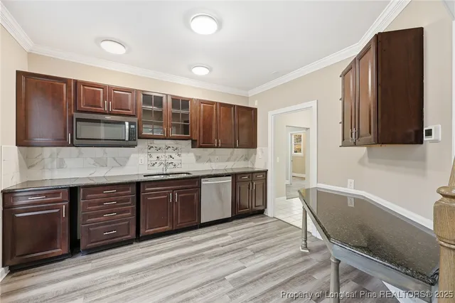 a kitchen with stainless steel appliances granite countertop wooden cabinets a stove top oven a sink and dishwasher