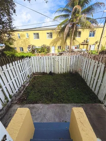 a view of a swimming pool with a patio and wooden fence