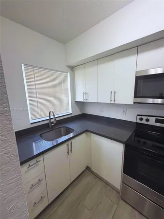 a kitchen with stainless steel appliances granite countertop a sink stove and cabinets