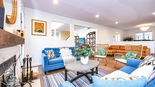 a living room with furniture kitchen view and a wooden floor