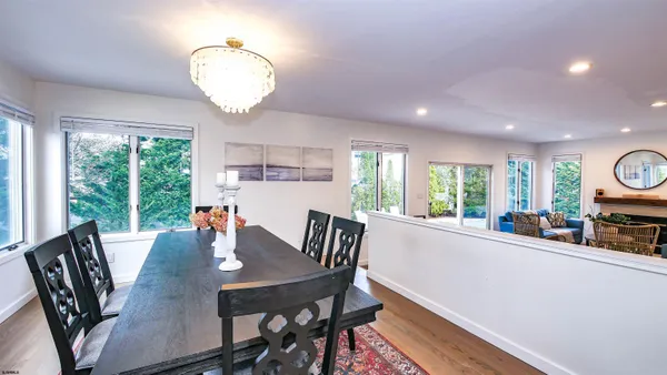 a kitchen with stainless steel appliances kitchen island granite countertop a refrigerator a oven a sink a dining table and chairs with wooden floor