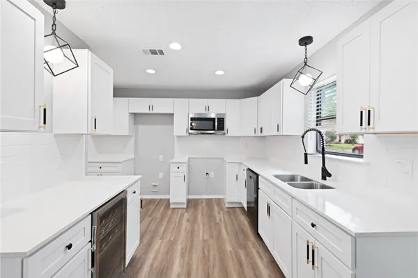 a kitchen with kitchen island granite countertop a sink cabinets wooden floor and stainless steel appliances