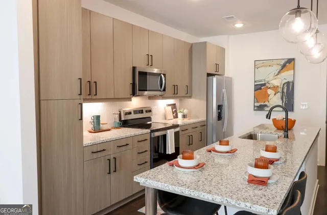 a kitchen with stainless steel appliances granite countertop a stove a refrigerator a sink a dining table and chairs