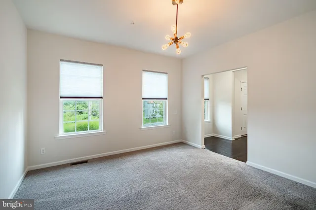 an empty room with windows chandelier fan and windows