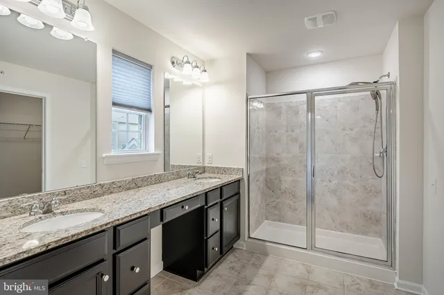 a bathroom with a granite countertop sink a mirror and a shower