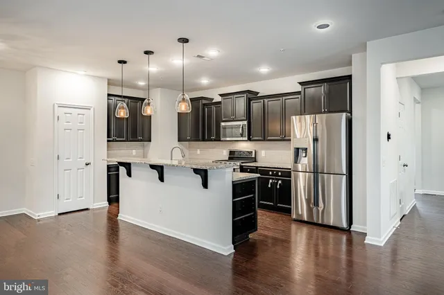 a kitchen with stainless steel appliances kitchen island granite countertop a refrigerator and a stove top oven