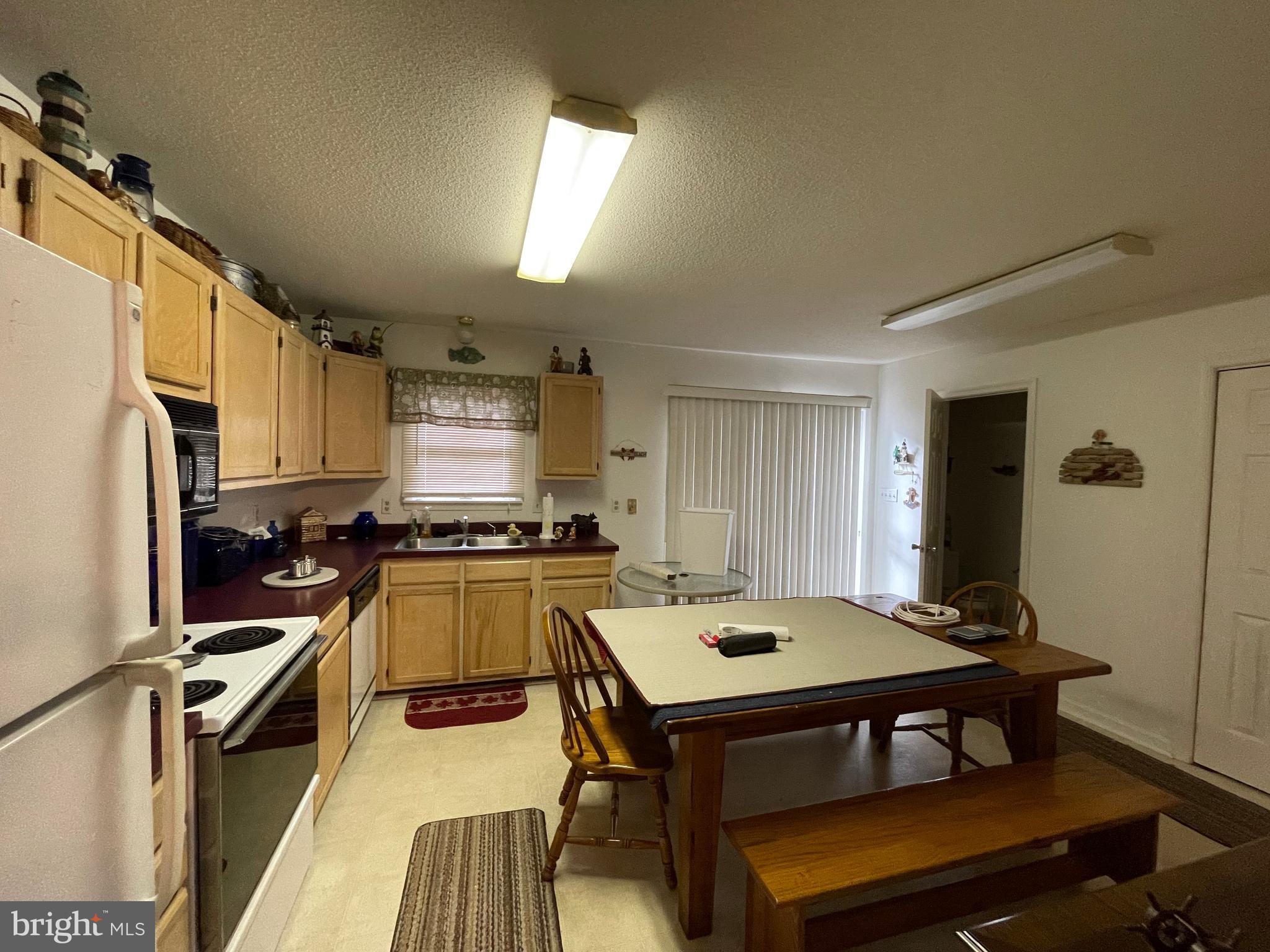 153 Captains Quarters Road Ocean City, MD 21842 - Photo 5 of 22 a kitchen with a table chairs and refrigerator
