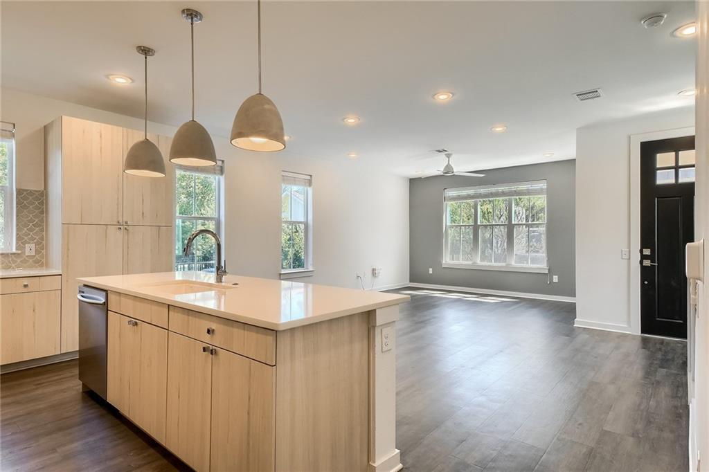 2624 Metcalfe Road, Unit 7 Austin, TX 78741 - Photo 8 of 31 Modern kitchen island with integrated sink, stainless steel dishwasher, and light wood-finish cabinetry