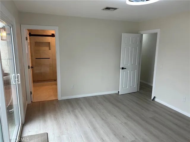 an empty room with wooden floor and a bathroom