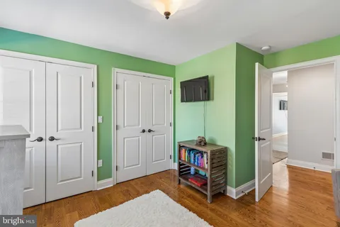 a view of an empty room with wooden floor and a bookshelf