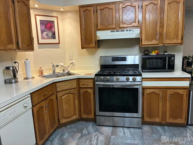 a kitchen with stainless steel appliances granite countertop a stove a sink and a microwave