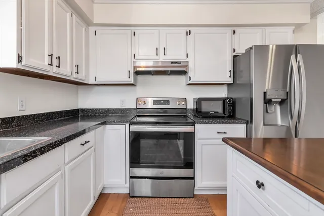 a kitchen with granite countertop white cabinets and stainless steel appliances