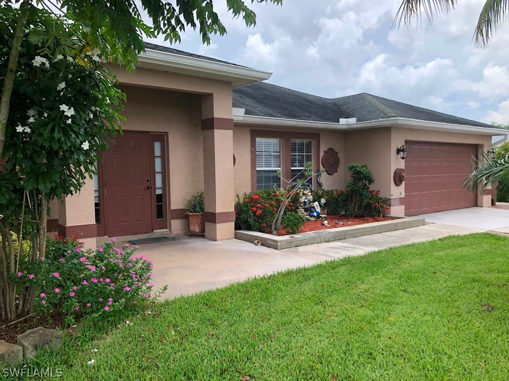 203 Roat Street Lehigh Acres, FL 33936 - Photo 2 of 15 a front view of house with yard and green space