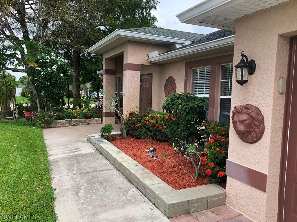203 Roat Street Lehigh Acres, FL 33936 - Photo 3 of 15 a front view of a house with garden