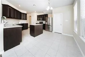 a kitchen with stainless steel appliances kitchen island granite countertop a refrigerator and a sink