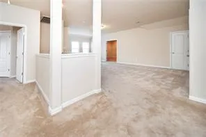 an empty room with kitchen view and entrance door