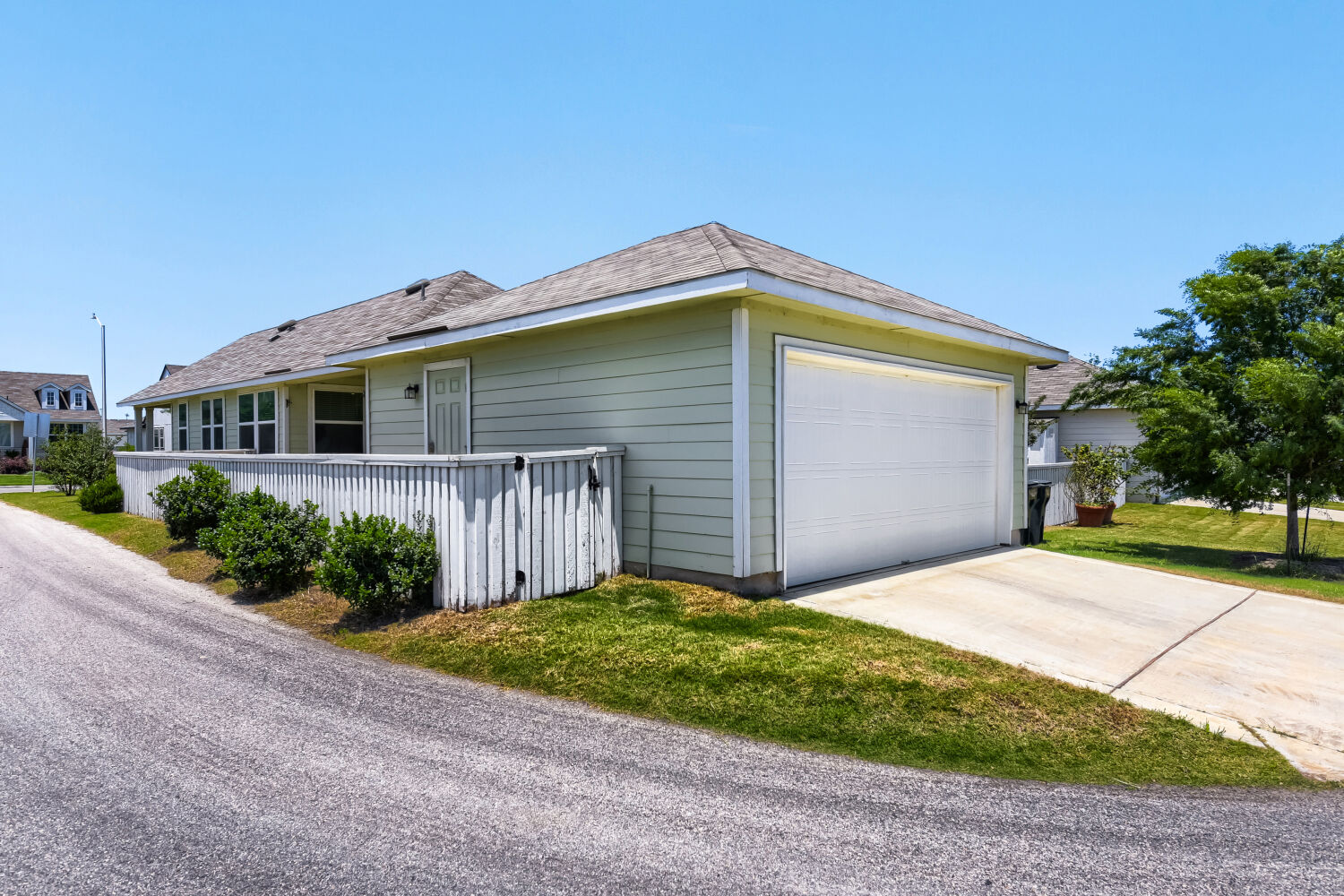 1310 Goforth Road Kyle, TX 78640 - Photo 24 of 24 Light green siding exterior featuring a white garage door, concrete driveway, and a white privacy fence