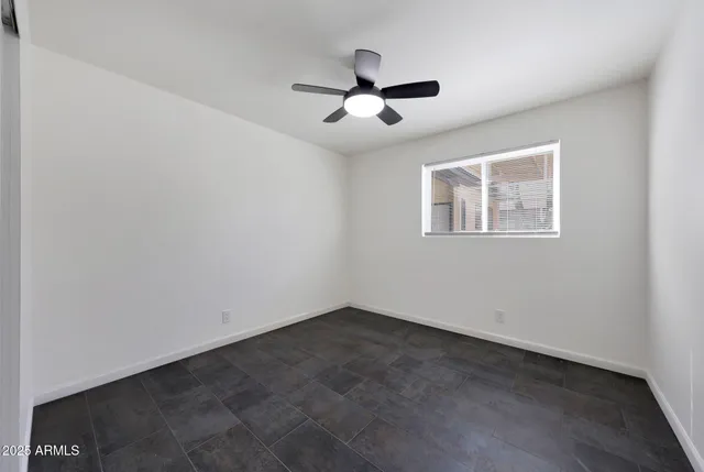 an empty room with a window and a fan