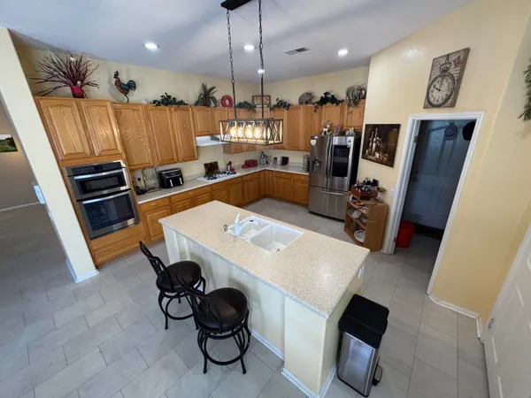 a kitchen with stainless steel appliances a stove a refrigerator a sink a dining table and chairs with wooden floor
