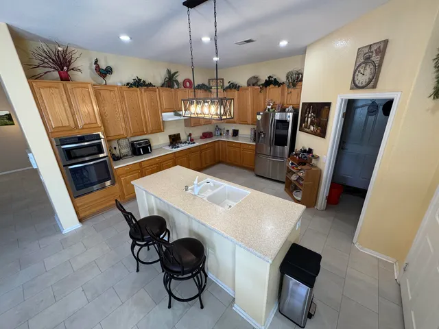 a kitchen with stainless steel appliances a stove a refrigerator a sink a dining table and chairs with wooden floor