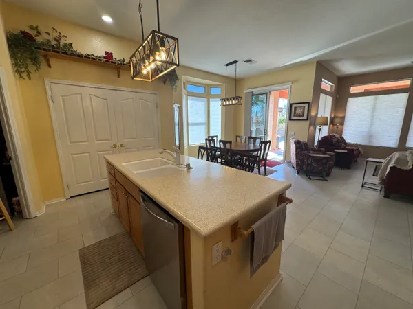 a kitchen with a sink a counter top space and living room view