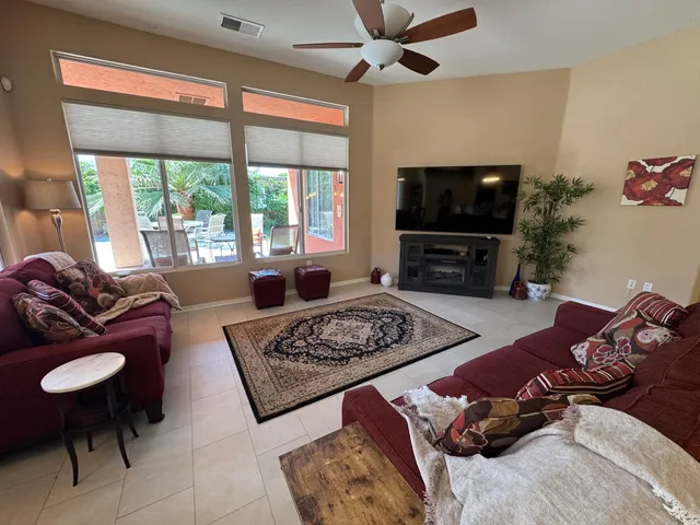 a living room with furniture a flat screen tv and a large window