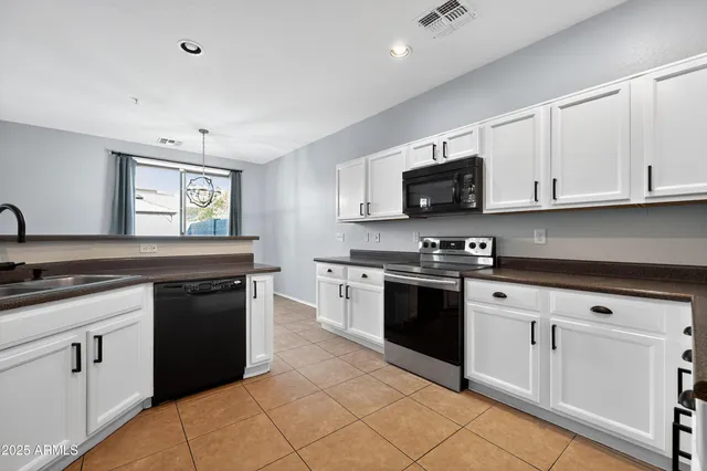a kitchen with granite countertop white cabinets and black appliances