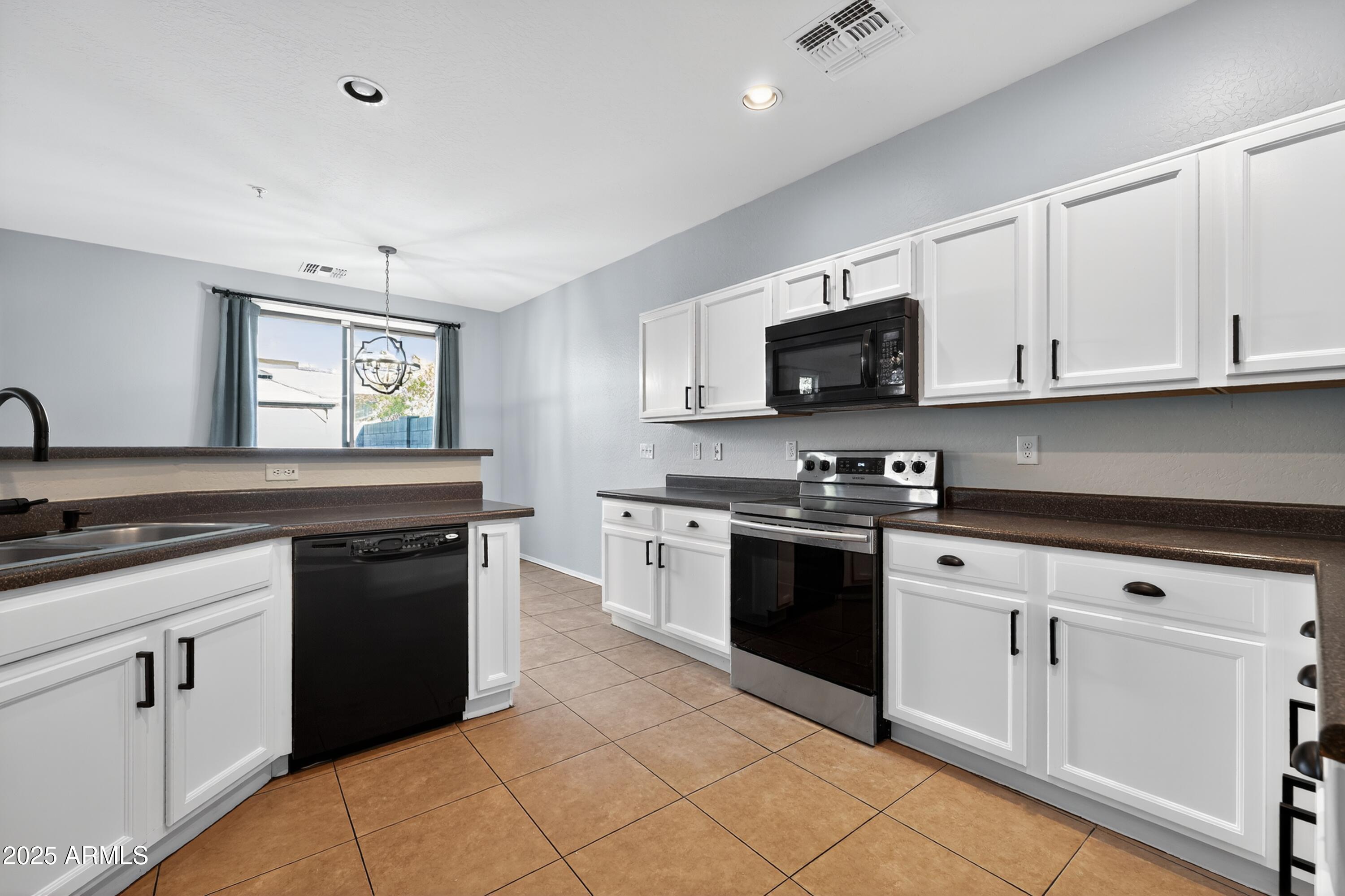 1250 South Rialto, Unit 31 Mesa, AZ 85209 - Photo 4 of 30 a kitchen with granite countertop white cabinets and black appliances