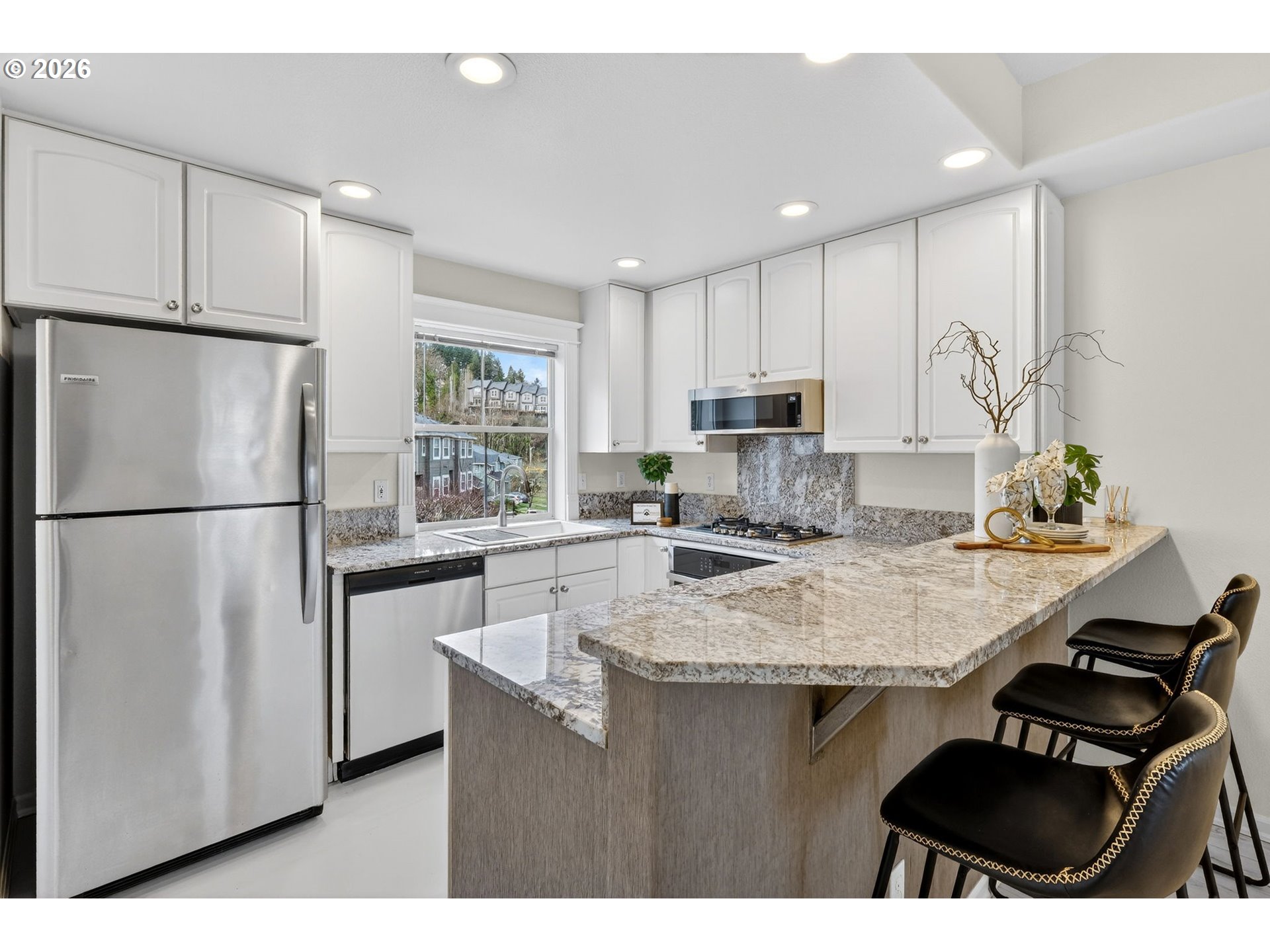 4934 Southwest 1st Avenue Portland, OR 97239 - Photo 11 of 33 a kitchen with kitchen island white cabinets a refrigerator a stove a sink and a refrigerator