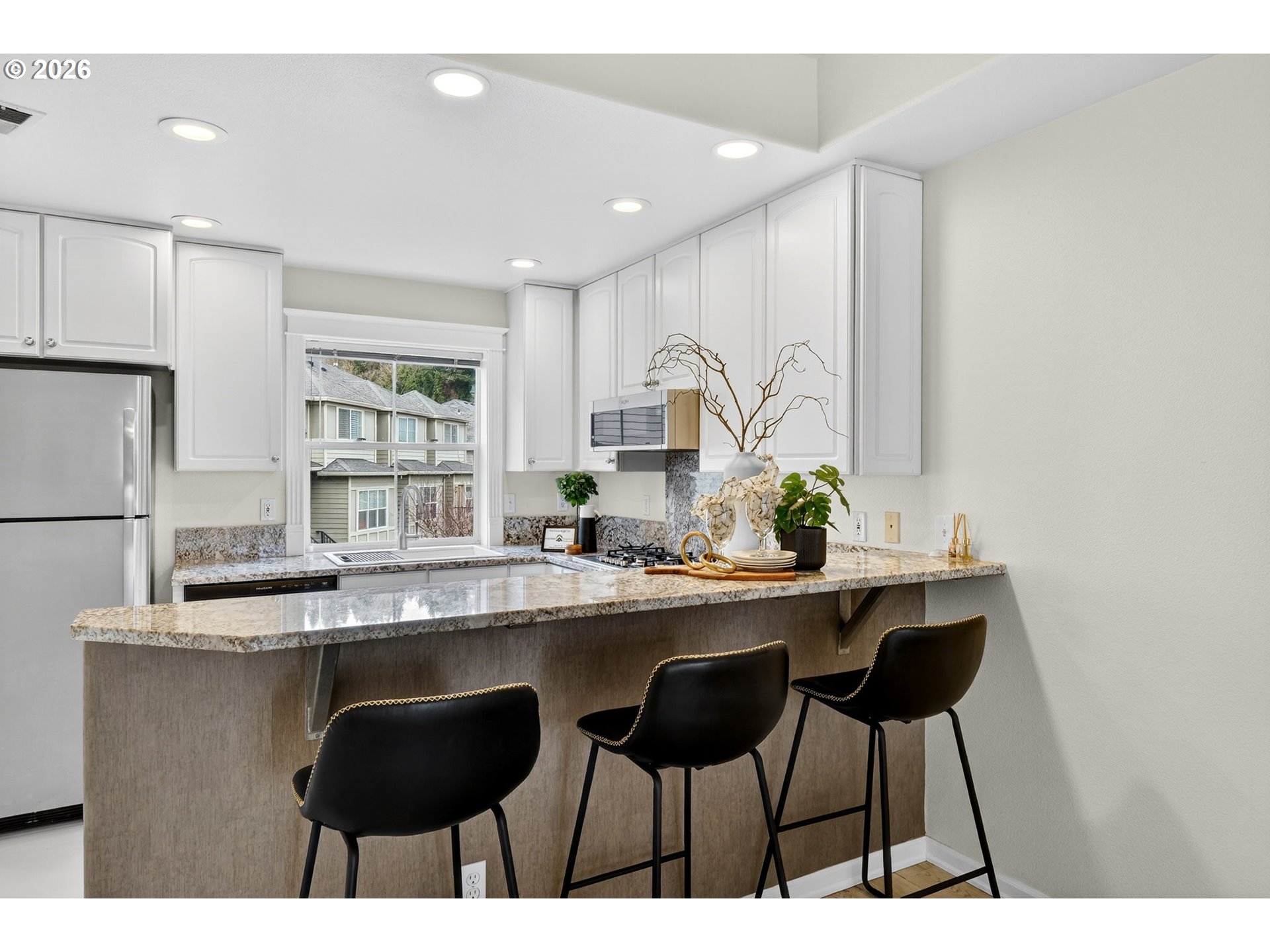 4934 Southwest 1st Avenue Portland, OR 97239 - Photo 10 of 33 a kitchen with a table chairs refrigerator and cabinets