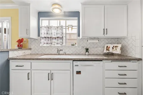 a kitchen with granite countertop white cabinets and a window