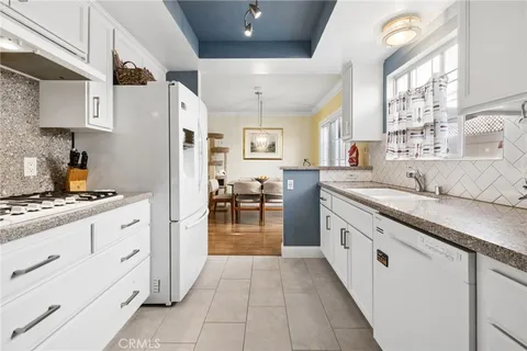 a kitchen with granite countertop cabinets a sink stainless steel appliances and windows
