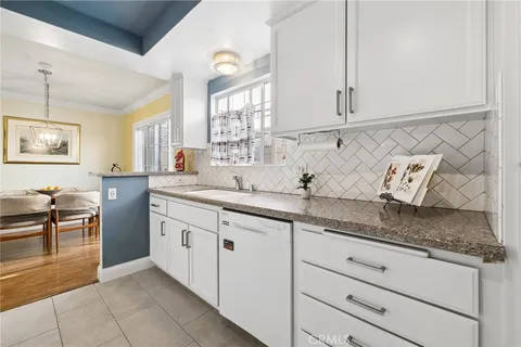 a kitchen with stainless steel appliances granite countertop a sink and dishwasher with white cabinets