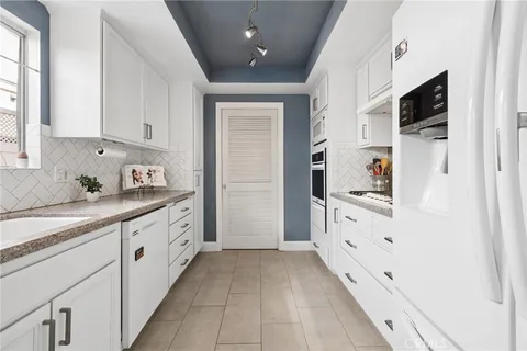 a large white kitchen with stainless steel appliances granite countertop a lot of counter space and a sink