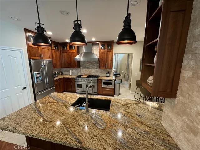 a kitchen with stainless steel appliances kitchen island granite countertop a sink refrigerator and cabinets