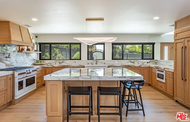 a large kitchen with granite countertop a stove a sink a dining table and chairs