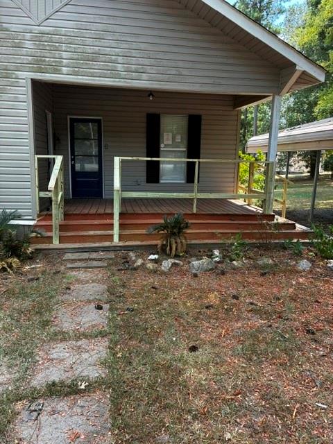 116 Gas Plant Road Doyline, LA 71023 - Photo 2 of 19 Front porch with wood decking and railing, featuring a dark-paneled entry door and black window shutters