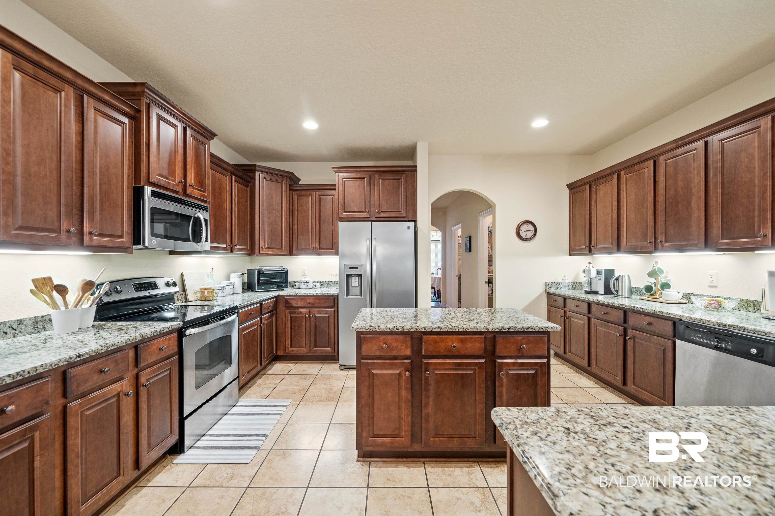 9115 Krystal Ridge Court Daphne, AL 36526 - Photo 11 of 39 Kitchen featuring light stone countertops, a center island, and stainless steel appliances