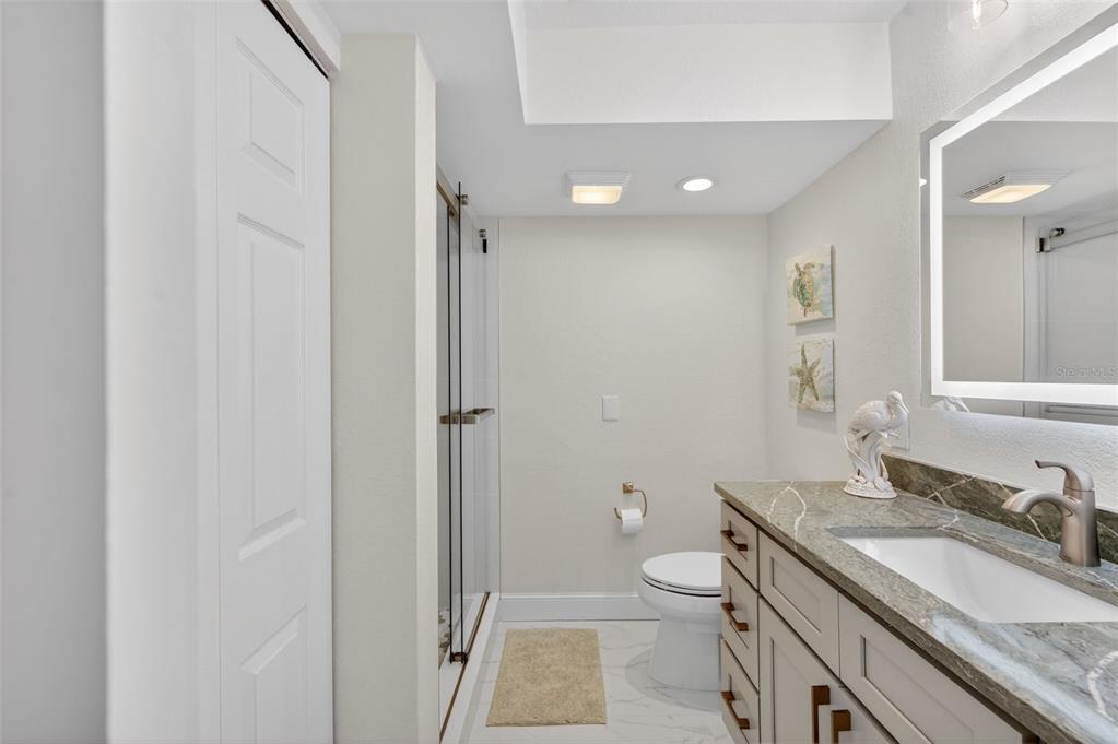 427 Boca Ciega Point Boulevard North St. Petersburg, FL 33708 - Photo 39 of 69 a bathroom with a granite countertop sink a toilet and a large mirror