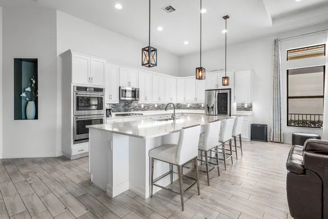 a kitchen with stainless steel appliances kitchen island granite countertop a table chairs and a refrigerator