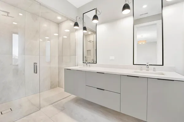 a bathroom with a double vanity sink mirror and shower