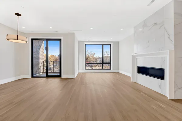 a view of an empty room with wooden floor fireplace and a window