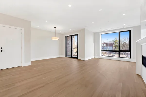 a view of an empty room with a window and wooden floor