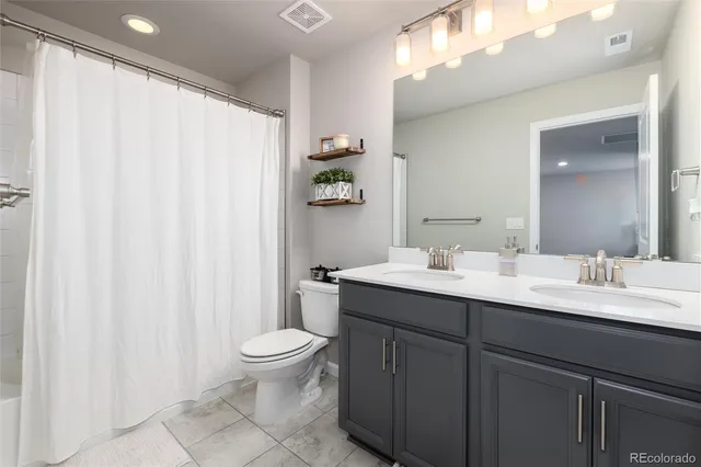 a bathroom with a double vanity sink toilet and a mirror