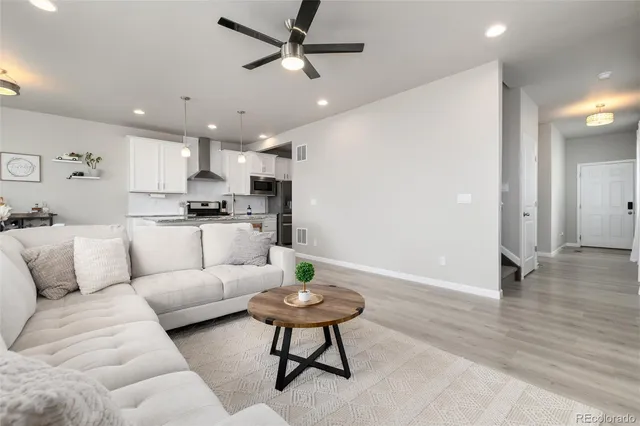 a living room with furniture a rug and kitchen view