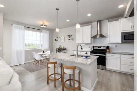 a kitchen with stainless steel appliances granite countertop a stove a sink a microwave a island with a dining table and chairs