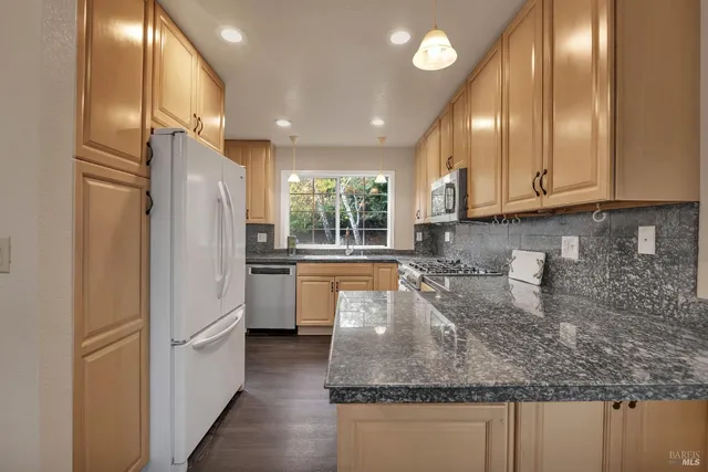 a large kitchen with stainless steel appliances granite countertop a stove a sink and a granite counter tops with wooden floors