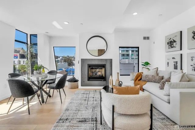 a living room with furniture a fireplace a rug and a large window