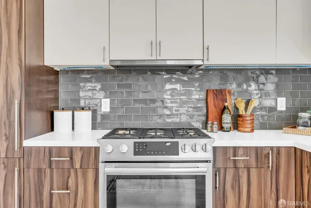 a kitchen with granite countertop a stove a sink and white cabinets