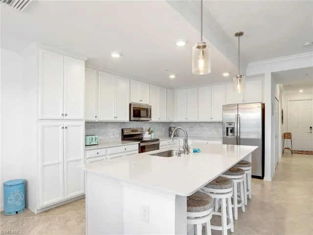 a kitchen with stainless steel appliances a microwave a stove a sink a refrigerator and white cabinets with wooden floor